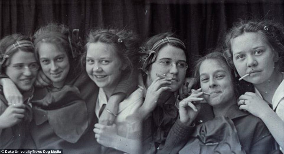 Grinning teenagers from the USA, pictured around 1900, post while puffing on cigarettes
