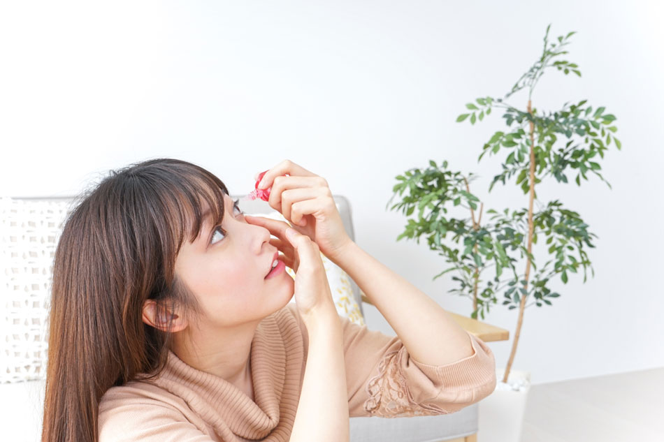 Young woman applying eye drops